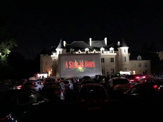 Cinéma drive-in devant un château éclairé.