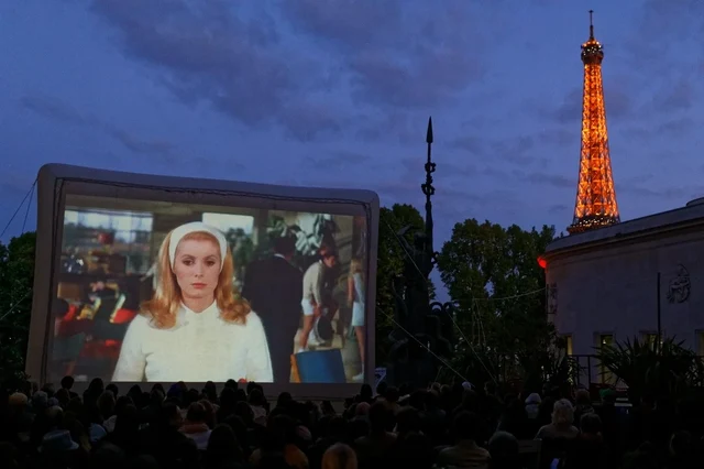 Cinéma en plein air devant la tour Eiffel, avec le public face à un écran gonflable.