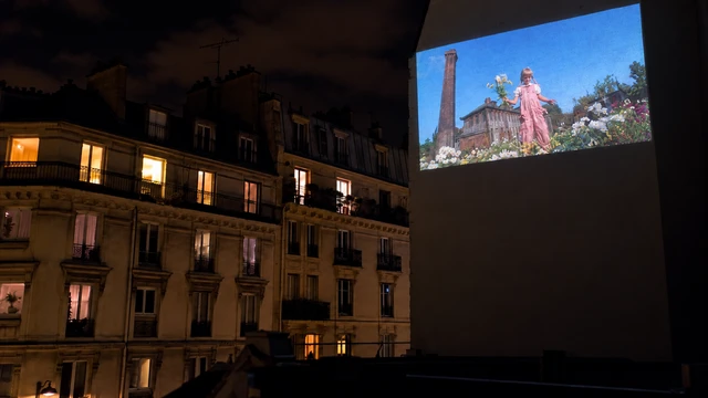 Projection de cinéma sur un mur au-dessus des toits de Paris.