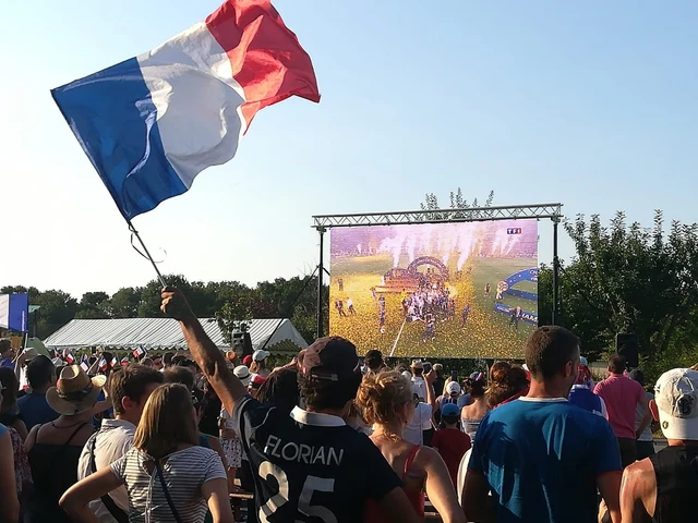Retransmission sportive sur écran LED avec un supporter agitant un drapeau français.