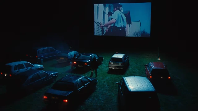 Séance de cinéma drive-in de nuit, avec les voitures face au grand écran.